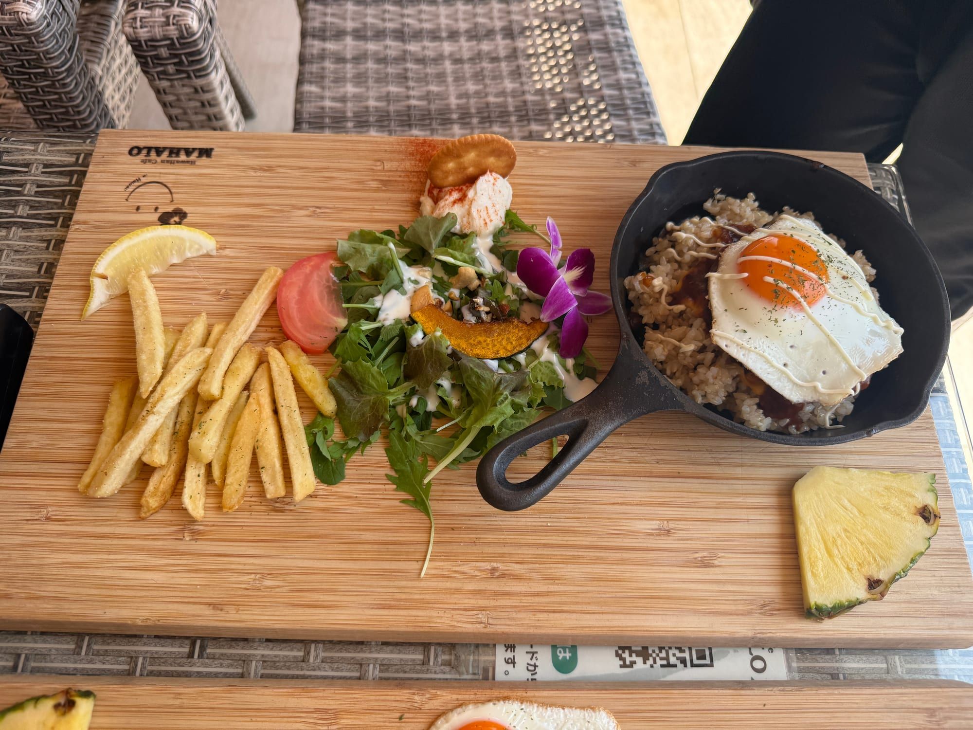目玉焼きがのったごはんとサラダ、フライドポテト、パイナップルが並んだ木のプレート
